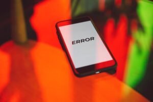A smartphone displaying an 'ERROR' message surrounded by vibrant red and green reflections indoors.